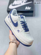Close-up side view of a white Nike Air Force 1 '07 Low sneaker with blue Swoosh branding, blue outsole accents, and perforated toe box.