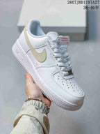 Angled side view of the white low-top sneaker with pale beige Swoosh, perforated toe box, Air-branded midsole, and textured outsole.