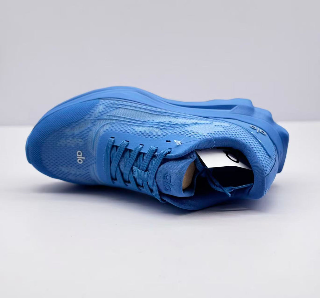 Top-side view of a blue Alo sneaker showing the textured upper, laces and padded collar.