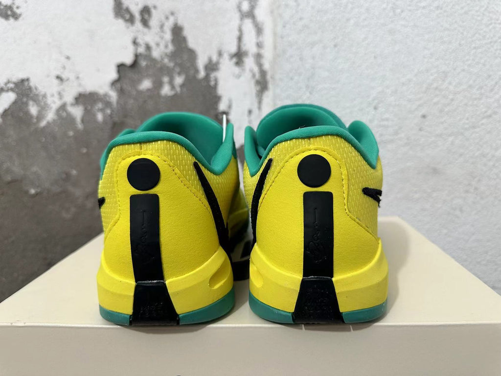 Rear view of green and yellow low-top basketball shoes with black heel accents.