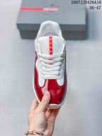 Top view of a red and white lace-up sneaker with a white tongue and vertical red Prada branding.