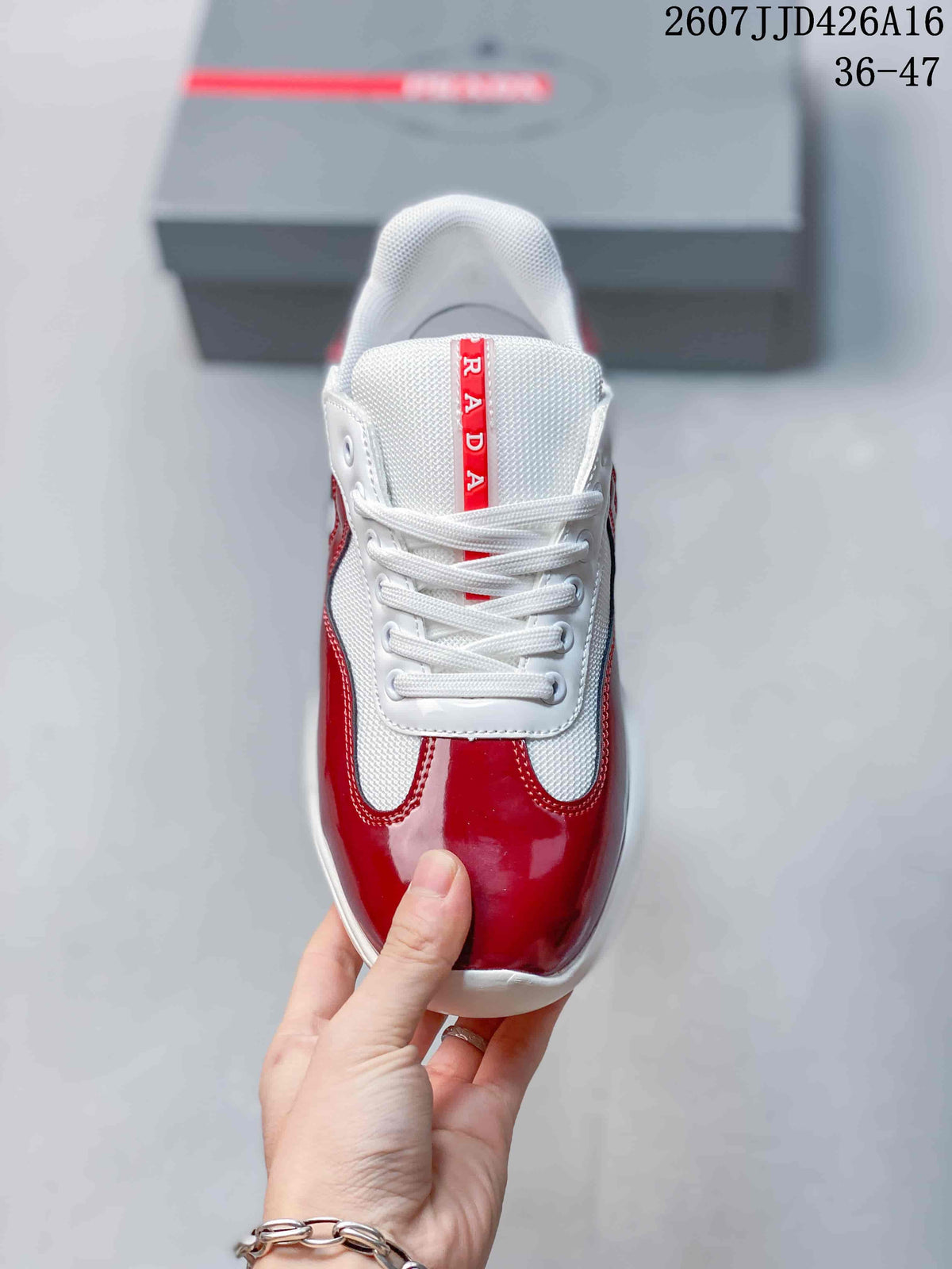 Top view of a red and white lace-up sneaker with a white tongue and vertical red Prada branding.