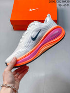 Side profile of the white shoe with a dark Swoosh and sculpted orange and pink midsole.