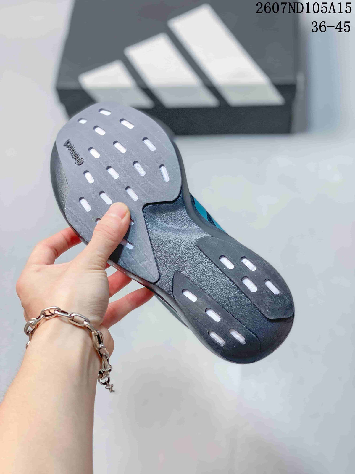 Close-up of the dark outsole showing multiple elongated tread openings and a patterned surface.
