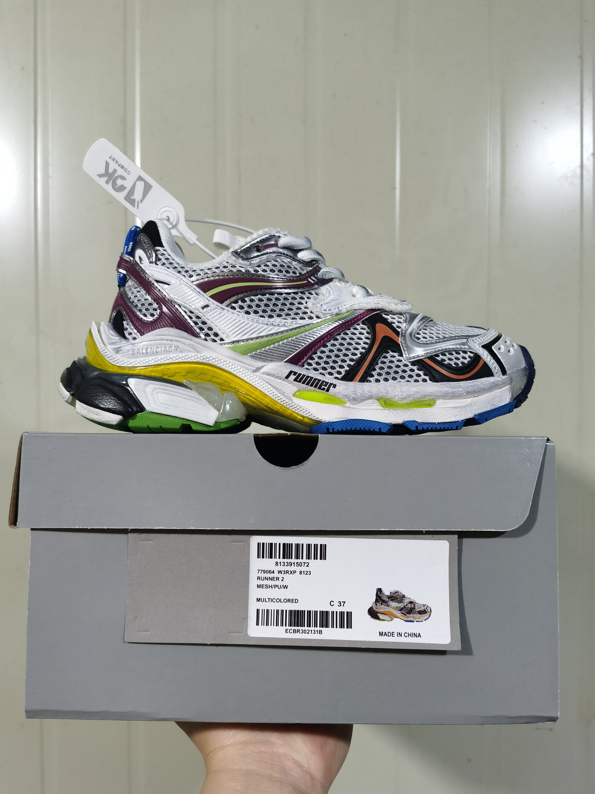 Side profile of the sneaker above its box; the box label shows Balenciaga Runner 2, style 8123, multicolor and size C 37.