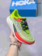 Angled side view showing Hoka branding, green upper, coral accents, and the white sculpted sole.