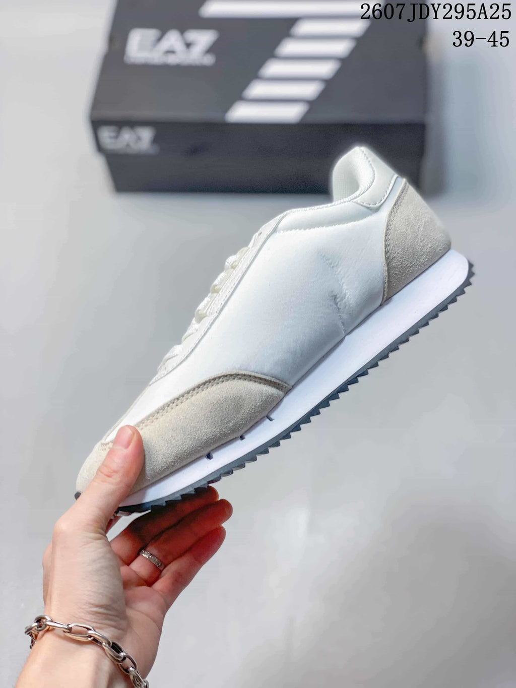 Side view of the white and light beige sneaker showing the layered upper and dark ridged outsole.