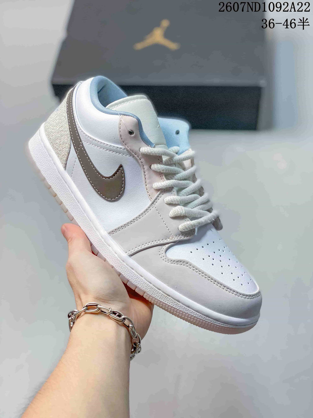 Predominantly white low-top Jordan sneaker with a taupe Swoosh and pale blue collar lining.
