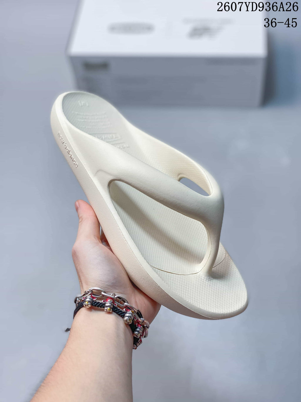 Angled side view of the off-white sandal showing the textured footbed, toe post, and New Balance branding on the side.
