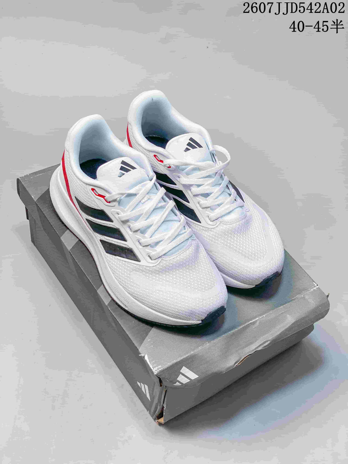 Pair of white Adidas Runfalcon 5 shoes with black side stripes and red accents on a shoe box.
