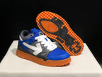 Angled view showing one sneaker's gum-colored outsole with black tread inserts and the blue, white, and grey upper.
