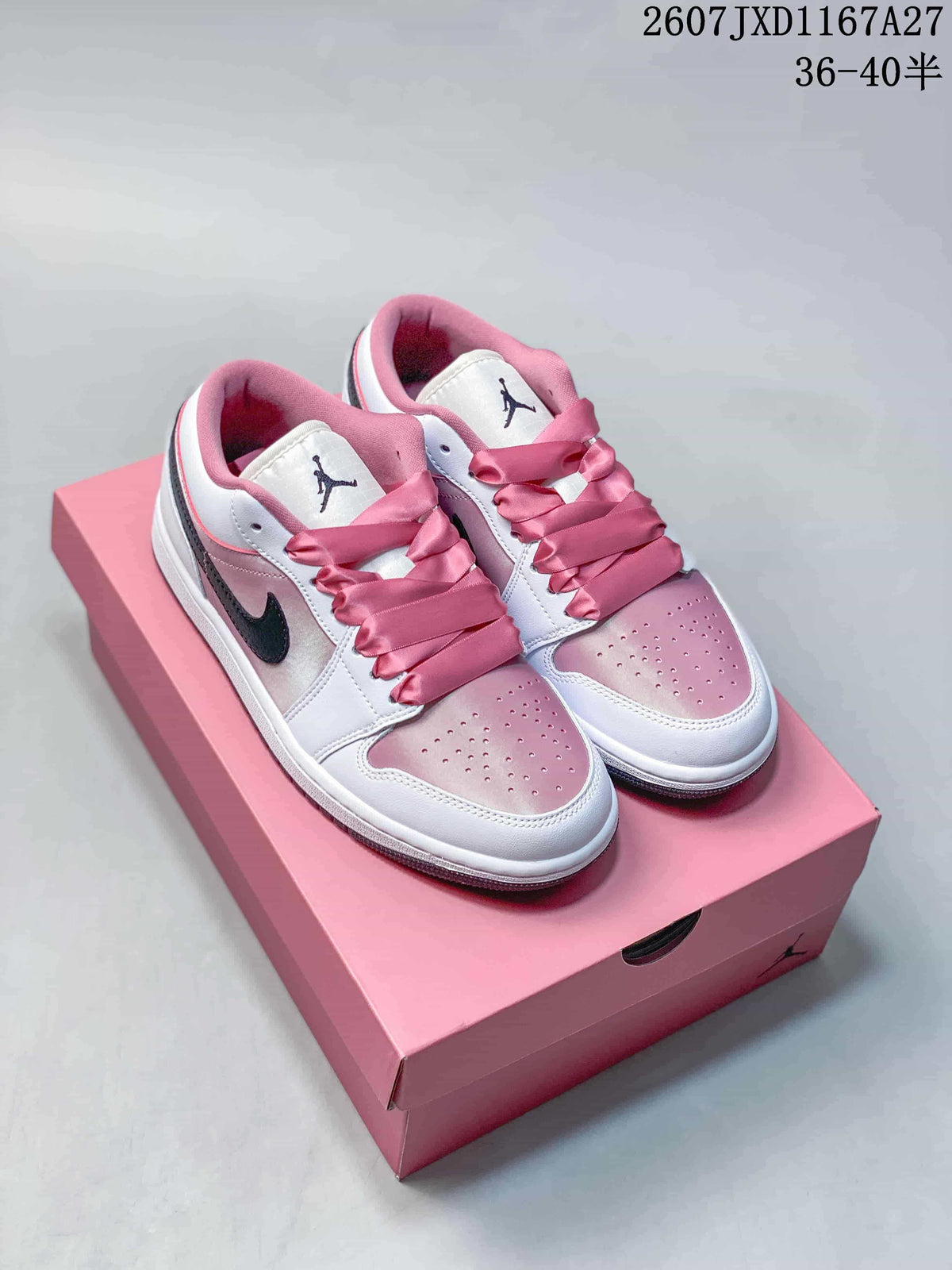 Pair of white and pink Nike Air Jordan 1 Low sneakers displayed on a pink shoe box.