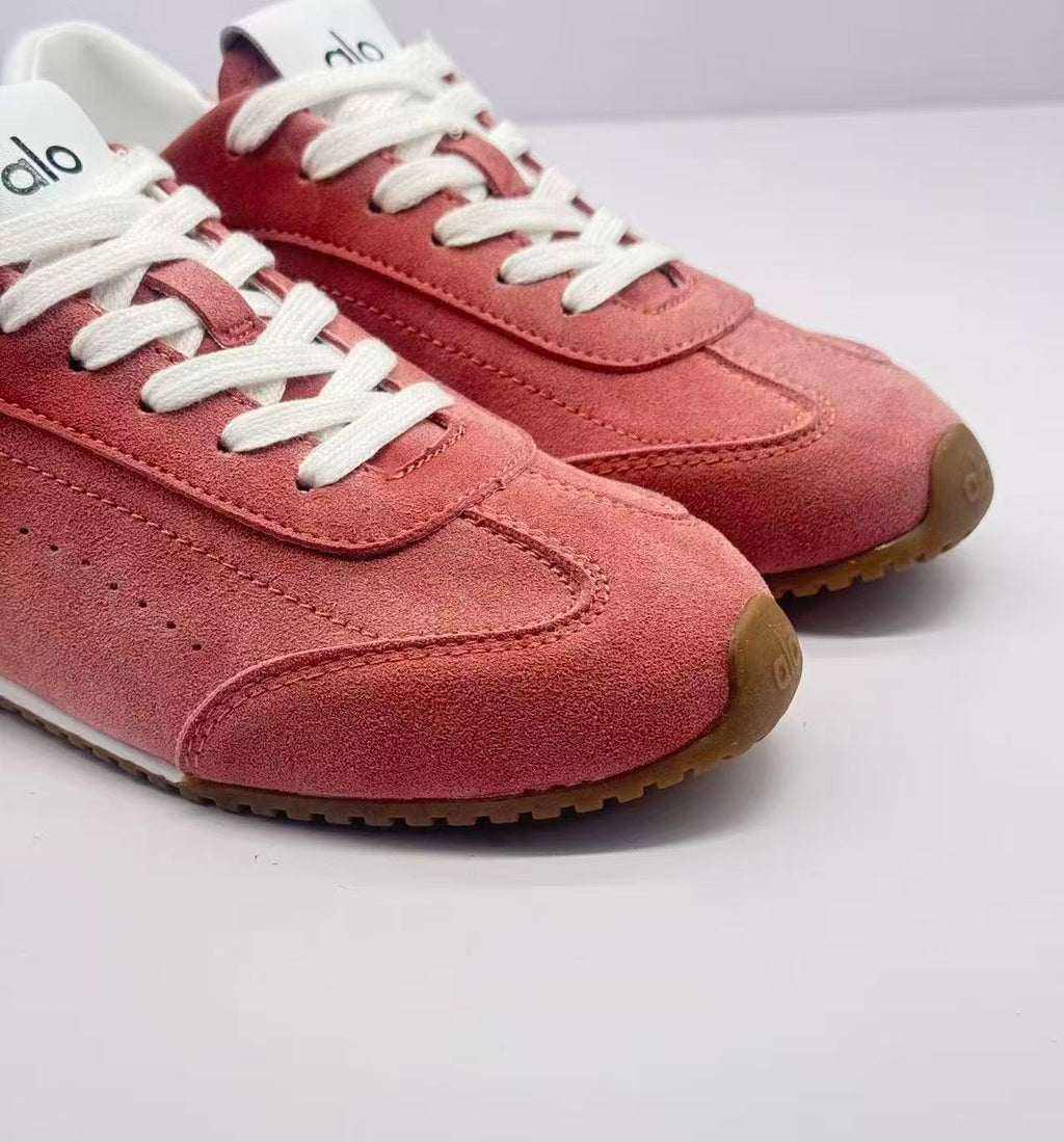 Close-up of the pink sneaker toe boxes, white laces and Alo tongue branding.