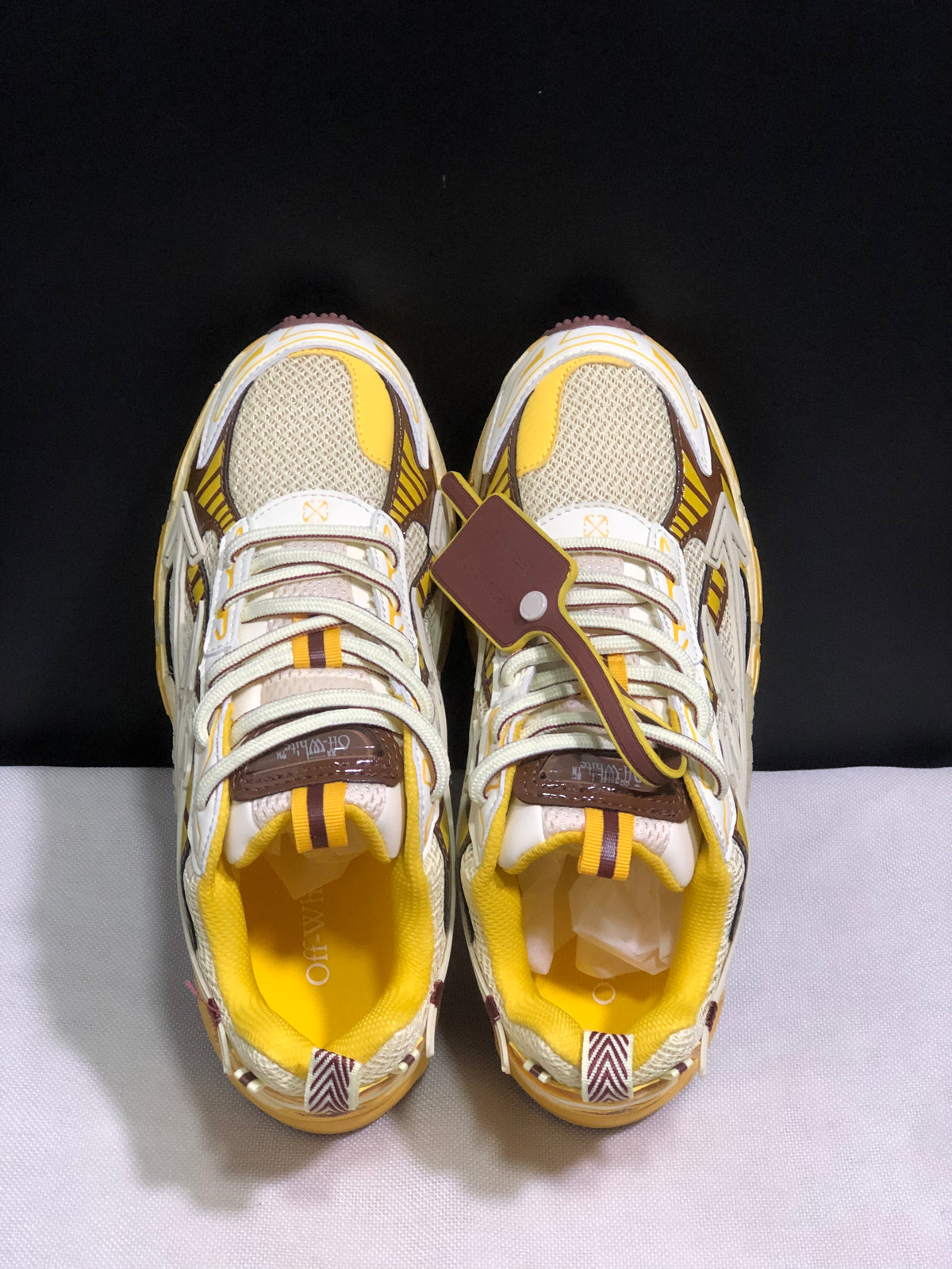 Top-down view showing the lace-up closure, mesh toe boxes, yellow lining, and removable-looking hangtag.