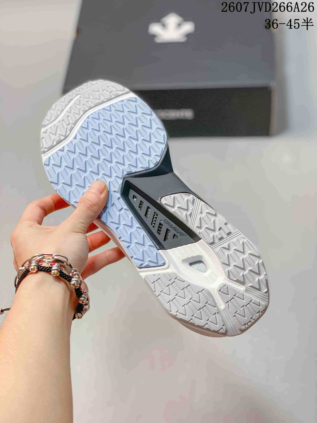 Close-up of the patterned outsole on the white sneaker, showing contrasting light blue and white tread sections.