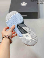 Close-up of the patterned outsole on the white sneaker, showing contrasting light blue and white tread sections.