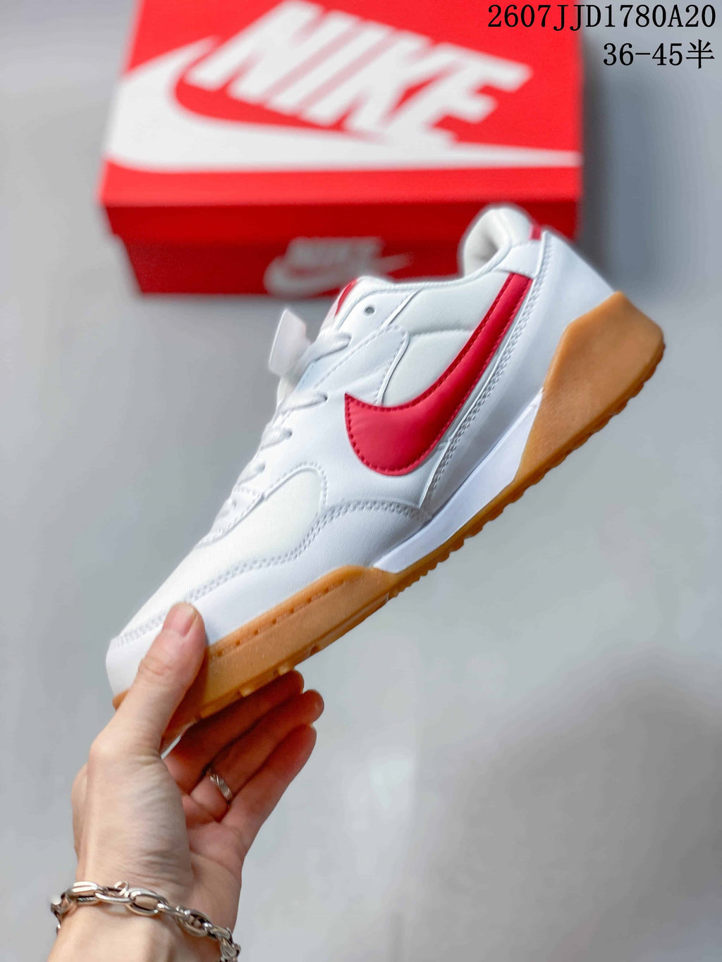 Side profile showing the white upper, red side accent, lace-up construction, and gum outsole.