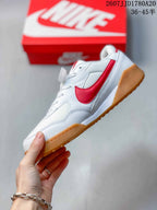Side profile showing the white upper, red side accent, lace-up construction, and gum outsole.