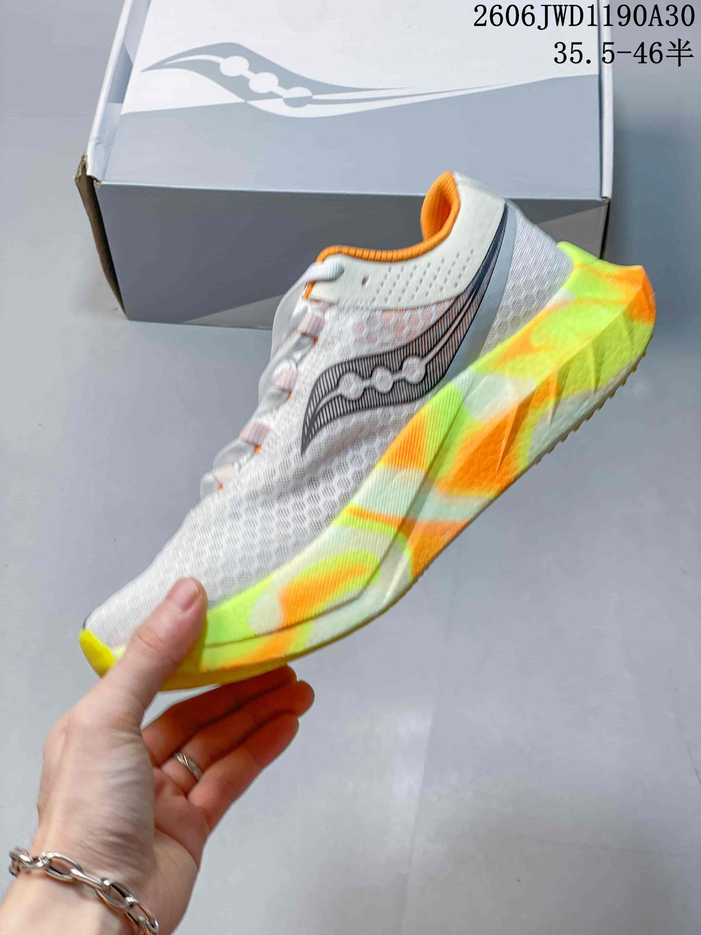 Side view of a white Saucony running shoe with dark side graphics and a multicolor sculpted sole.