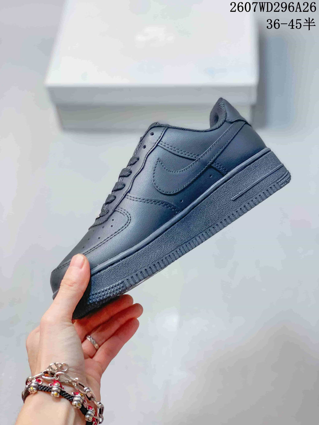 Side view of the black low-top sneaker showing the tonal Swoosh-style side panel, stitching, and raised sole.