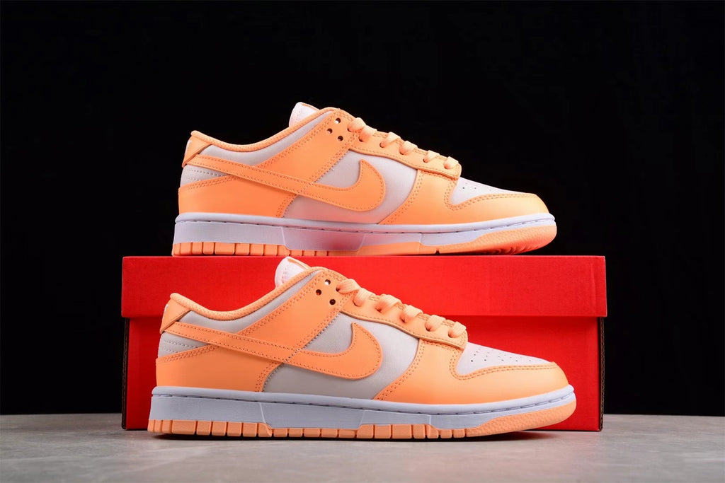 Pair of orange and light gray Nike SB low-top sneakers displayed on a red shoe box.