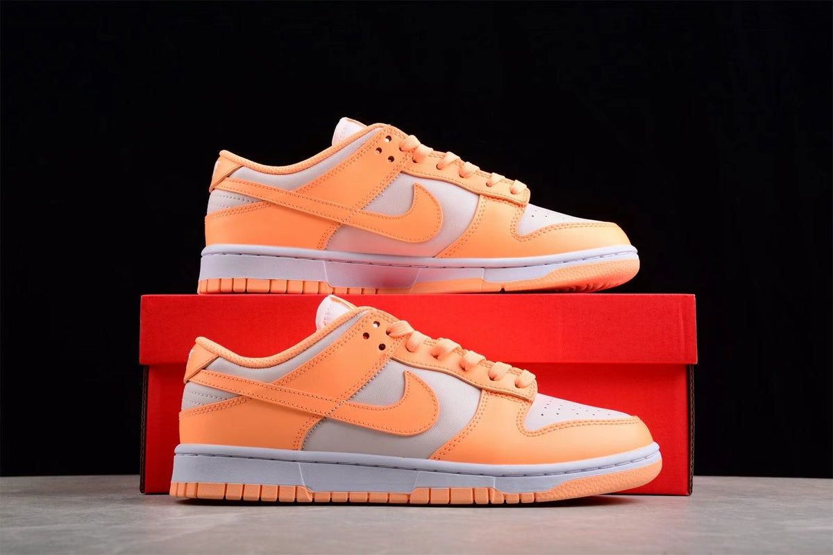 Pair of orange and light gray Nike SB low-top sneakers displayed on a red shoe box.
