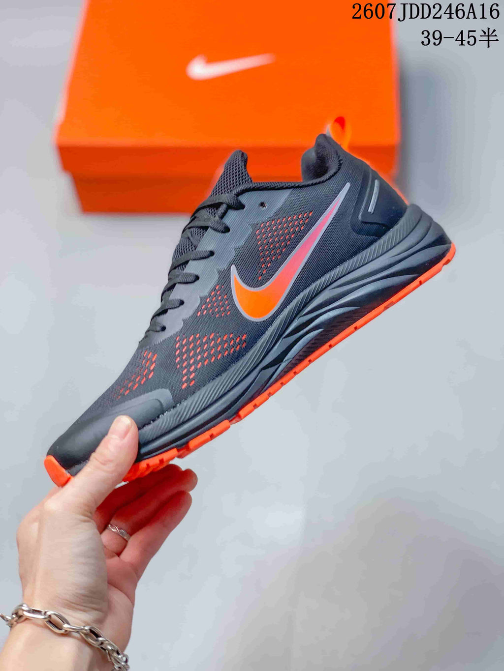 Side view of the dark gray running sneaker with orange Nike branding, mesh panels, and textured sole.