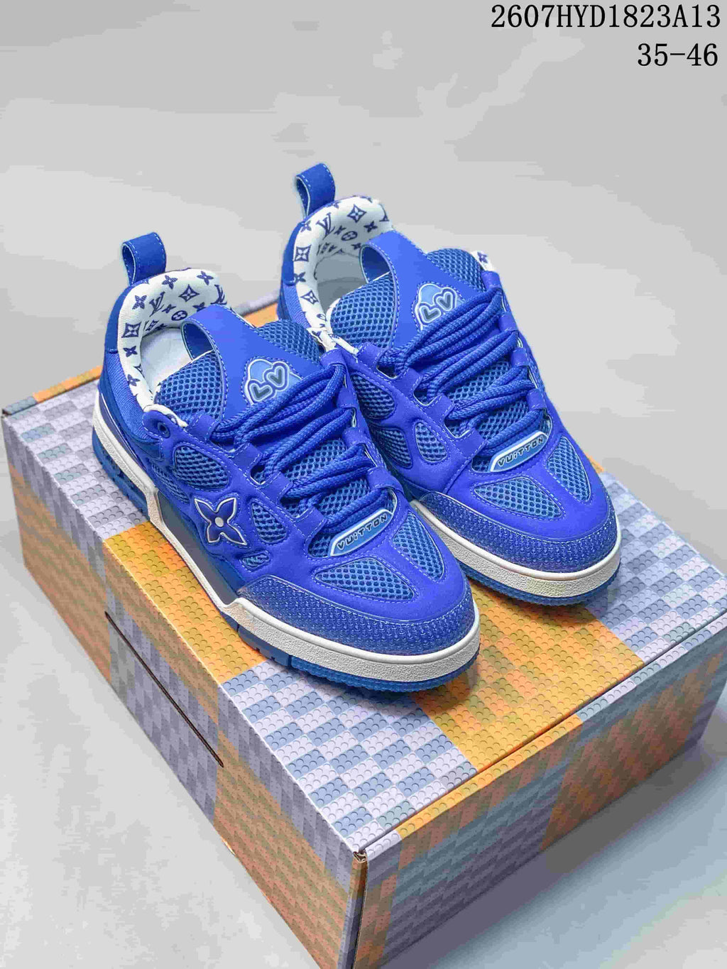 Pair of blue Louis Vuitton Trainer sneakers displayed on a patterned box, showing the front and side details.