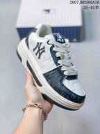 Angled side view of the white and navy MLB sneaker showing the side emblem, patterned panels, laces, and layered sole.