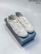 White and grey Onitsuka Tiger low-top sneakers displayed on a branded shoebox, with style code 2605 JDD294A14 and size range 36–41 visible.
