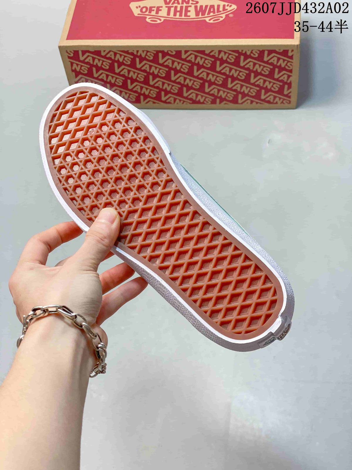 Bottom view of the sneaker showing its patterned outsole, with a Vans shoe box in the background.