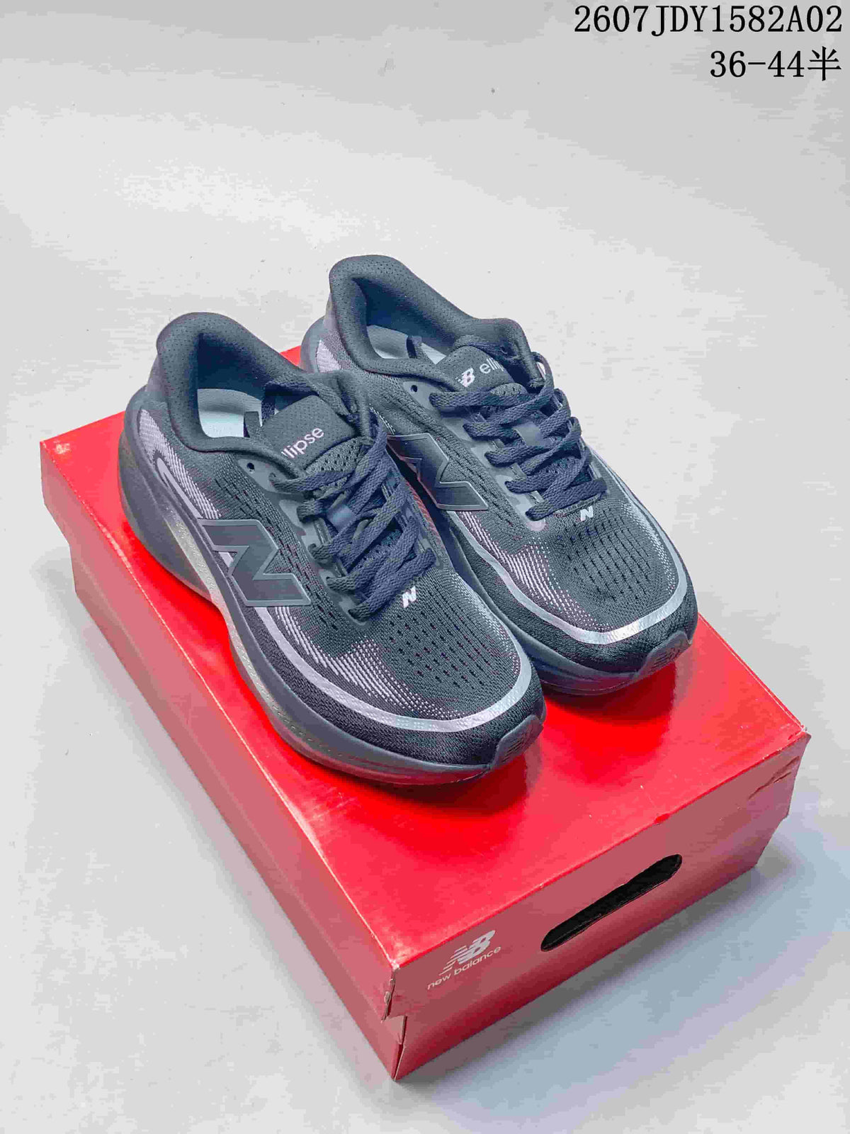 Pair of dark gray New Balance running shoes with purple-toned details, shown on a red shoe box