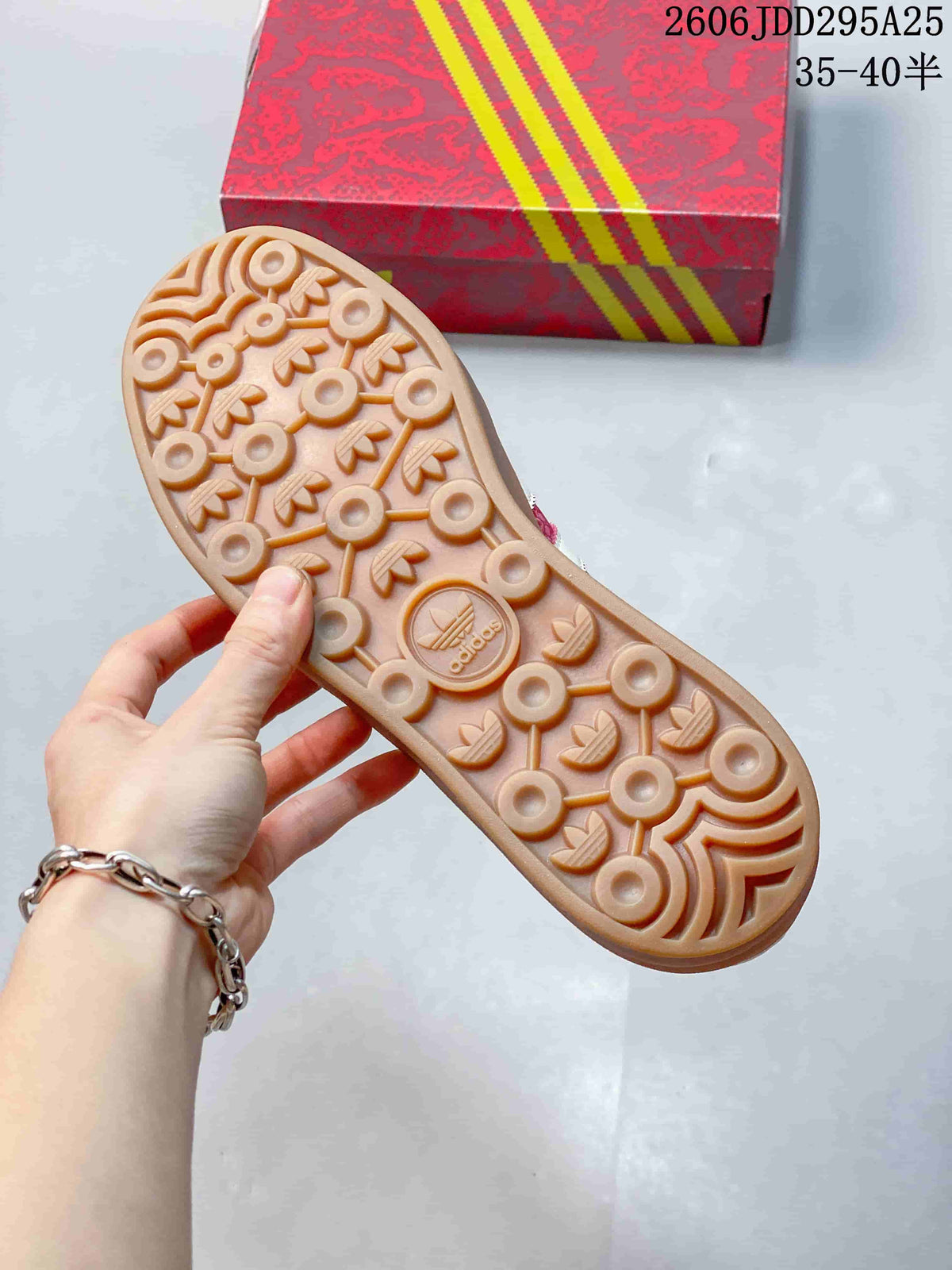 Underside of the sneaker showing a gum-colored outsole with circular and trefoil-shaped tread details.