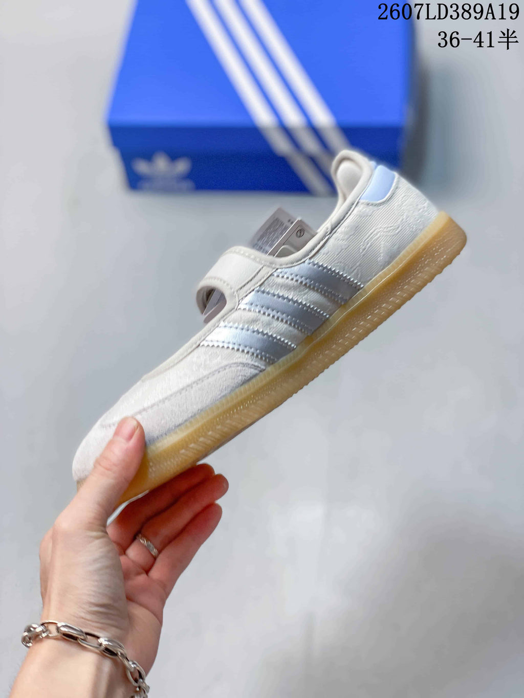 Side view of the white sneaker showing the silver stripes, hook-and-loop strap, and gum outsole.