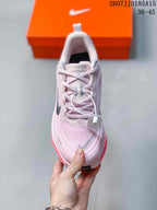 Top view of a pale pink lace-up running shoe showing the tongue, laces, side branding, and reflective-looking toe details.