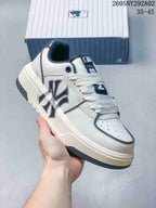 Angled side view of the sneaker showing the large MLB side logo, white upper, navy accents, and cream-colored sole.