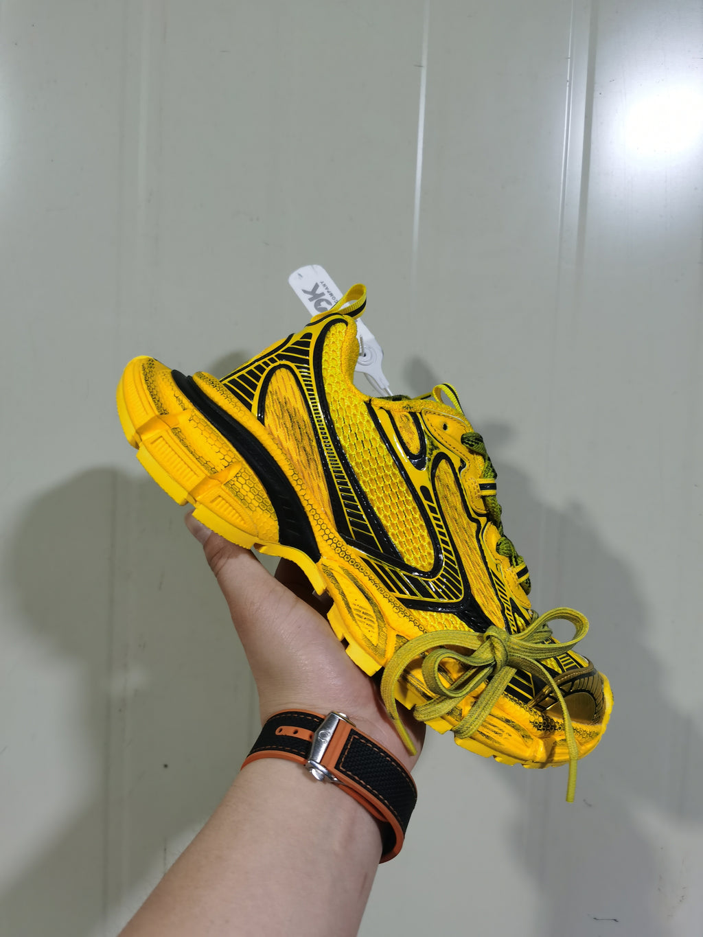 Angled view of the yellow and black sneaker showing the lace-up front, padded collar, side pattern, and outsole construction.