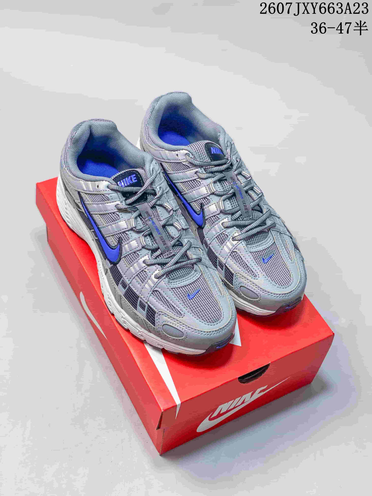 Pair of gray and blue Nike P-6000 sneakers displayed on a red shoebox.