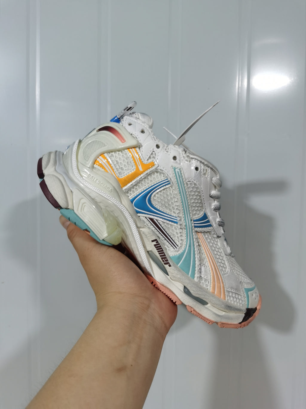 Close angled view of the white Balenciaga Runner sneaker showing layered side panels, mesh-textured sections, laces, and sculpted sole.