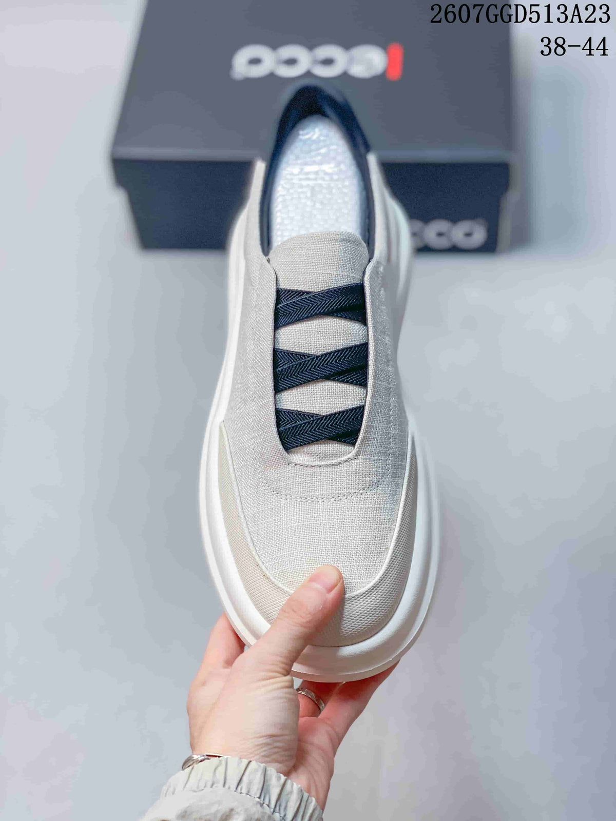 Top view of the light gray sneaker showing the rounded toe, navy crossover bands, and slip-on opening.
