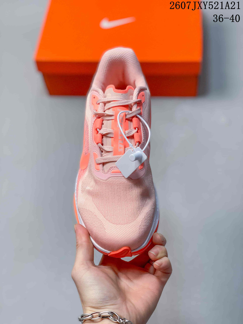 Top view of a pale pink and coral lace-up sneaker showing the textured toe box, tongue, laces, and attached security tag.