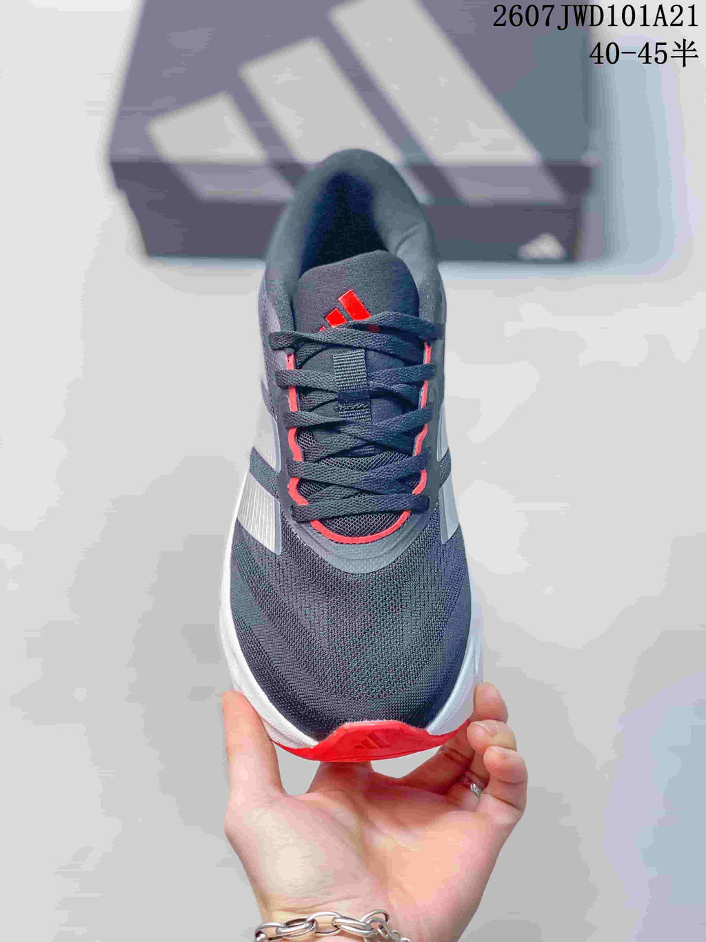 Top view of the sneaker showing the dark mesh-like upper, flat laces, padded tongue, and red details.