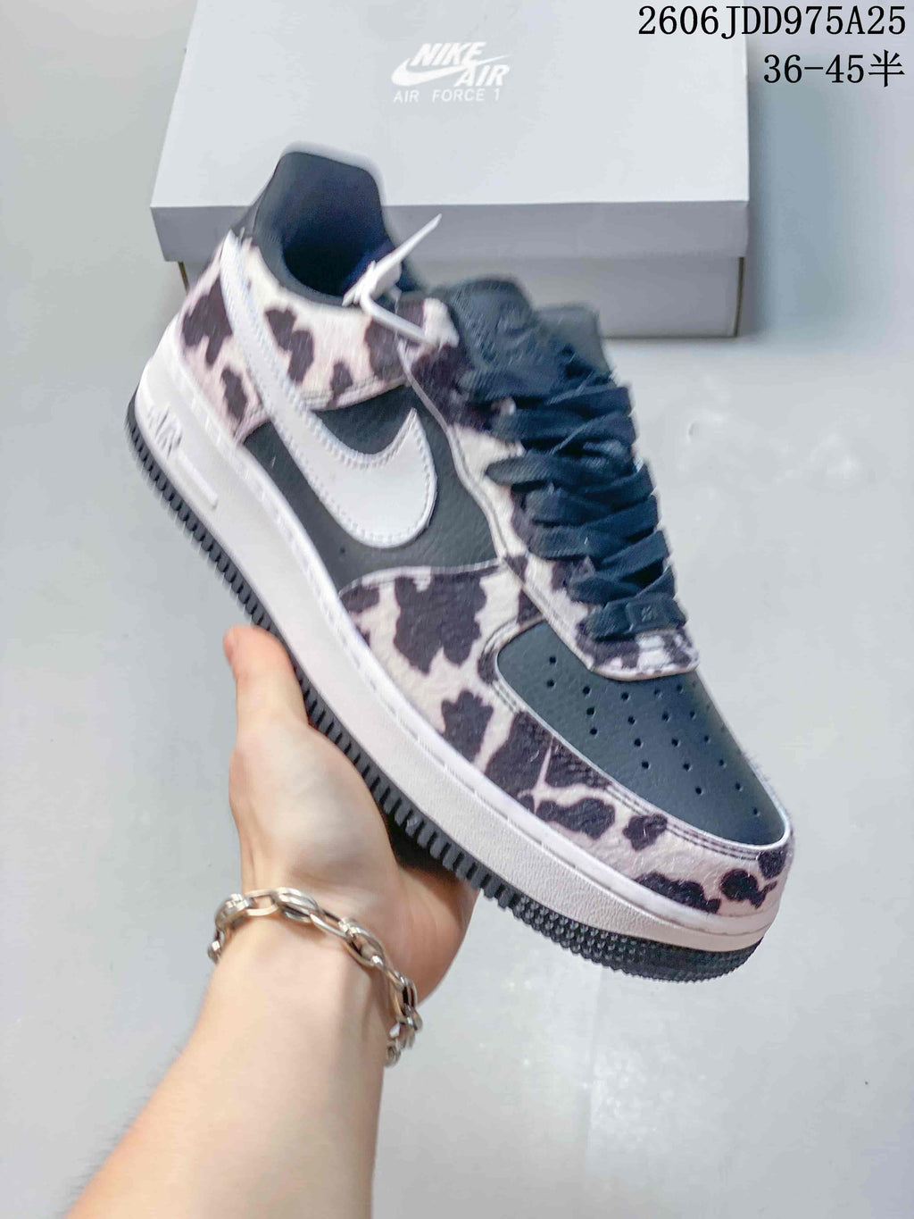 Side view of a dark sneaker with cow-print panels and white Swoosh