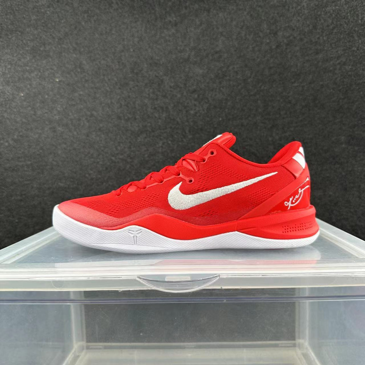 Red low-top Nike Kobe basketball shoe with white side branding and a white outsole