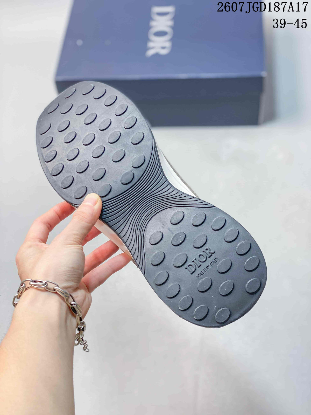 Underside view of a sneaker showing a dark outsole with oval traction elements and Dior branding.