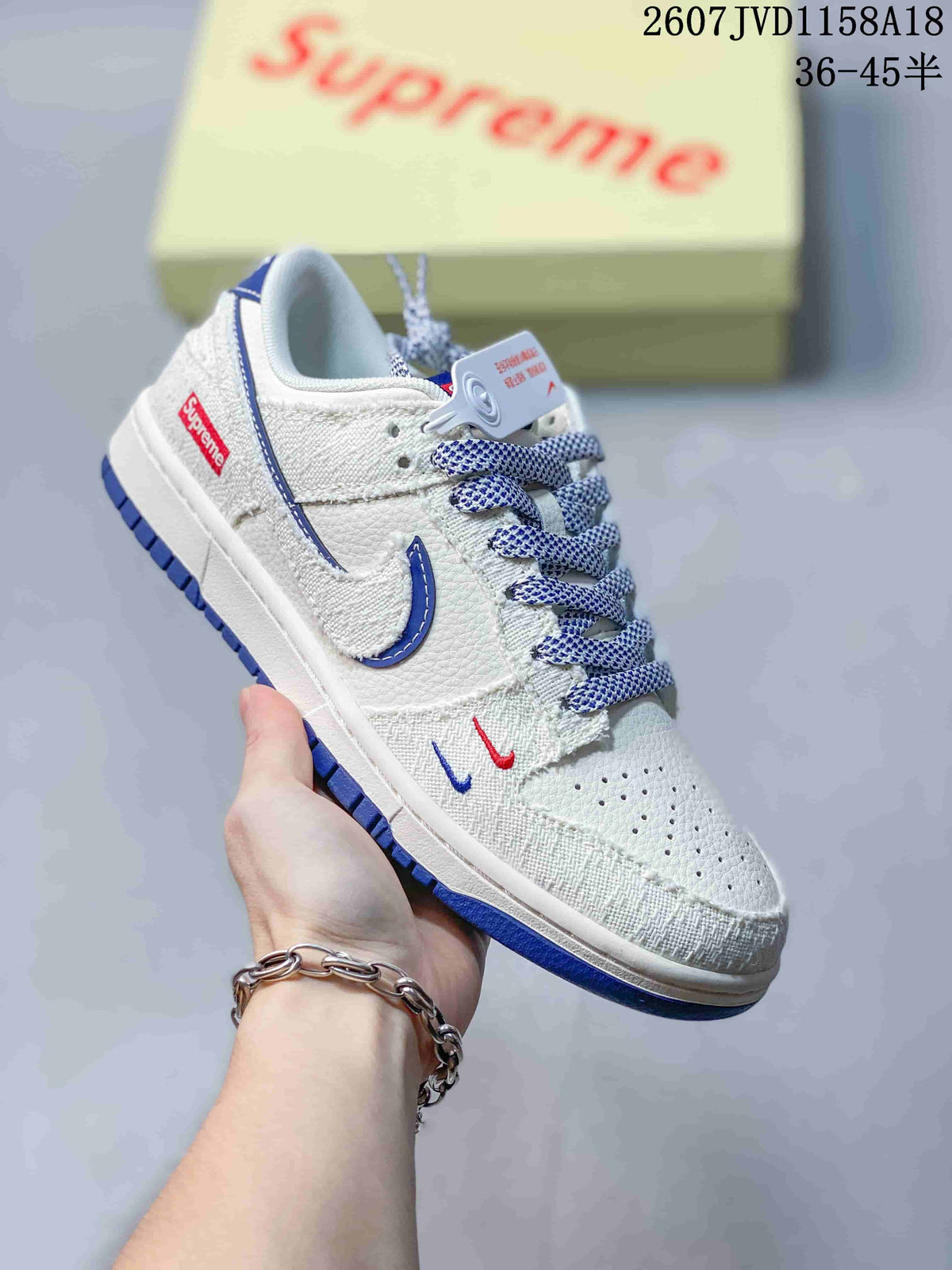 Close view of a white and gray sneaker with blue Swoosh details, blue outsole, patterned laces, and contrasting toe-box graphics.