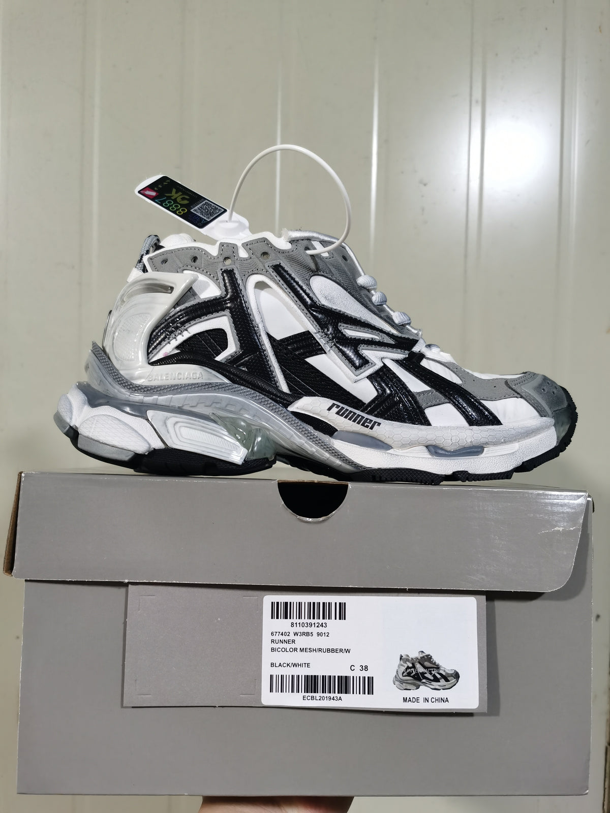 Balenciaga Runner sneaker displayed on its box, with the box label showing style code 677402 W3RB5 9012 and black/white color.