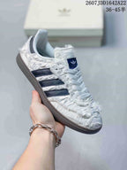 Close-up side view of a white ruched adidas Samba OG sneaker with dark three-stripe branding and a gum-style outsole.