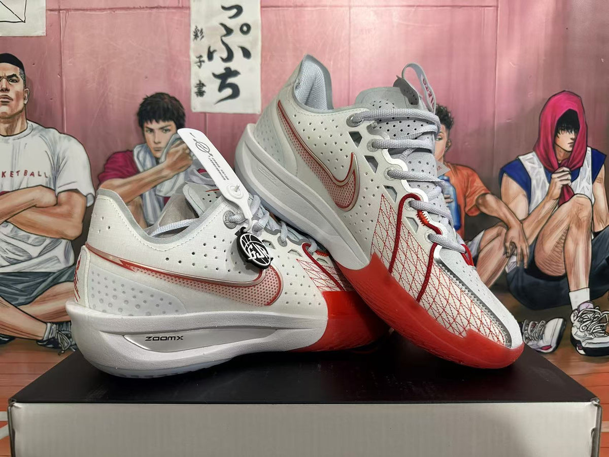 White and red Nike basketball shoes shown from the side, highlighting the laces, perforated panels, and red outsole.
