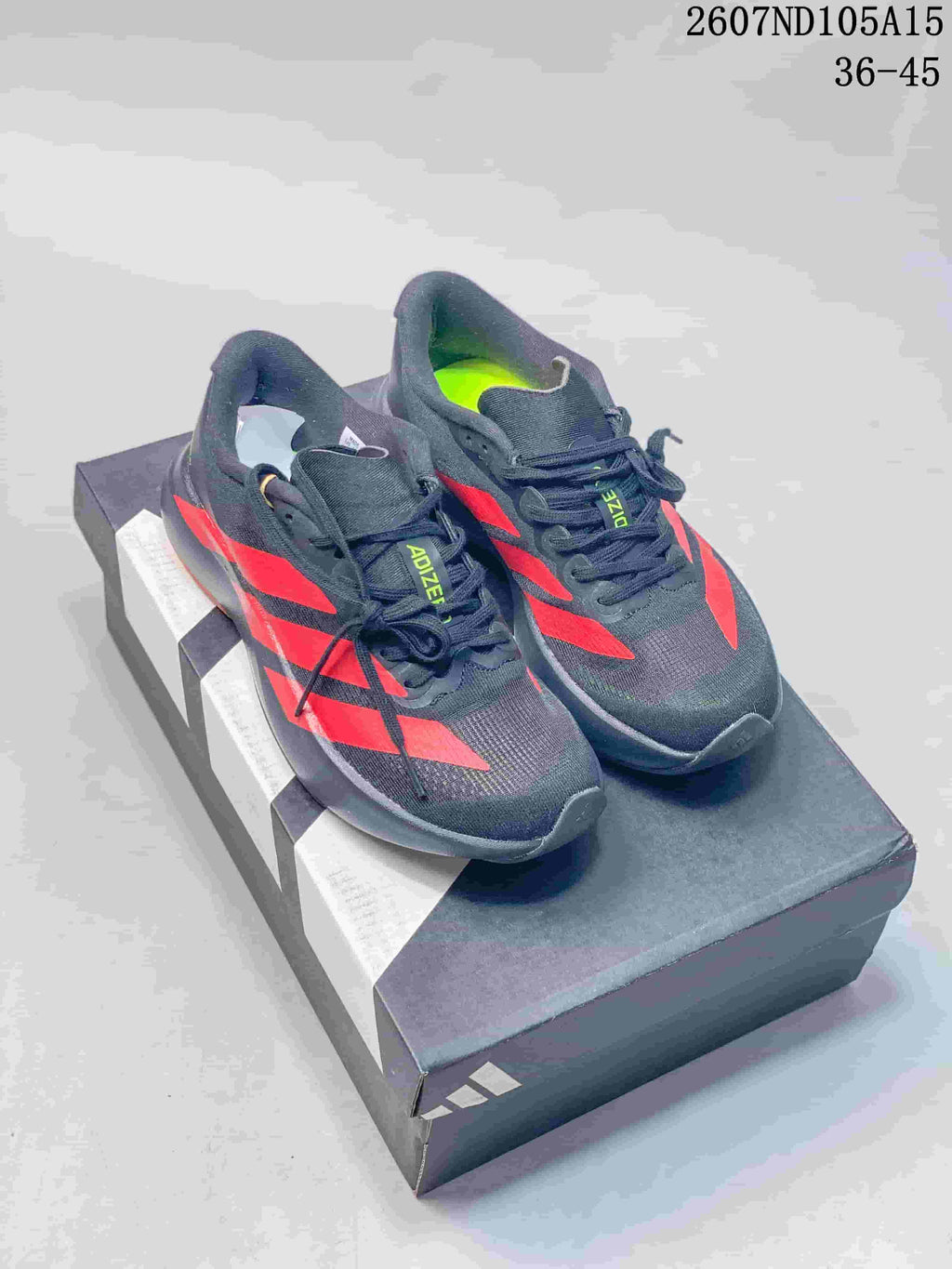 Black Adidas Adizero sneakers with bright red contrast stripes displayed on a shoebox.